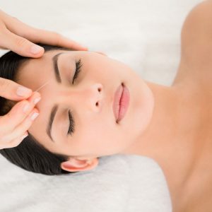 acupuncture to woman's forehead facial rejuvenation